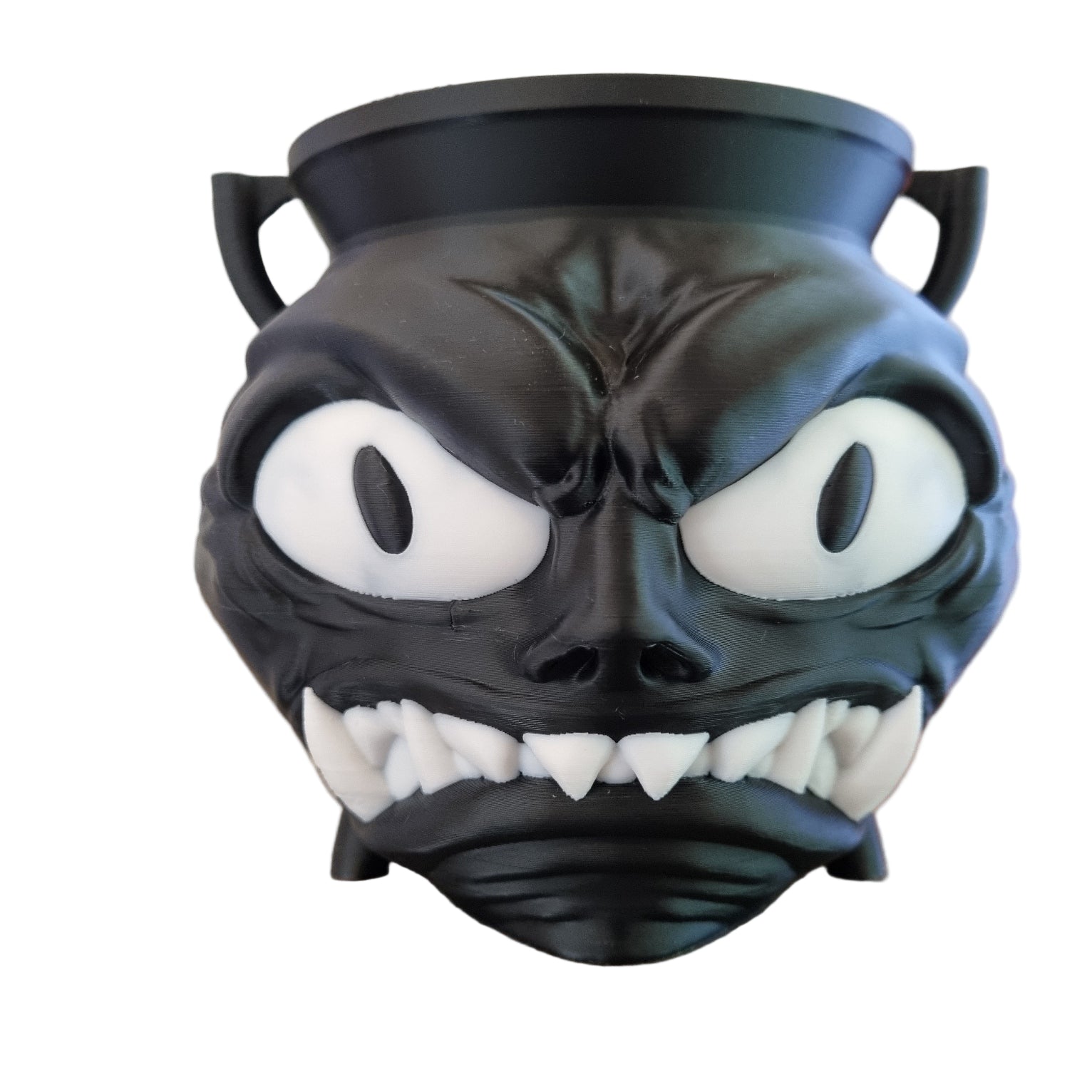 Black and white creature head with large eyes and sharp teeth. used as candy holder for Halloween